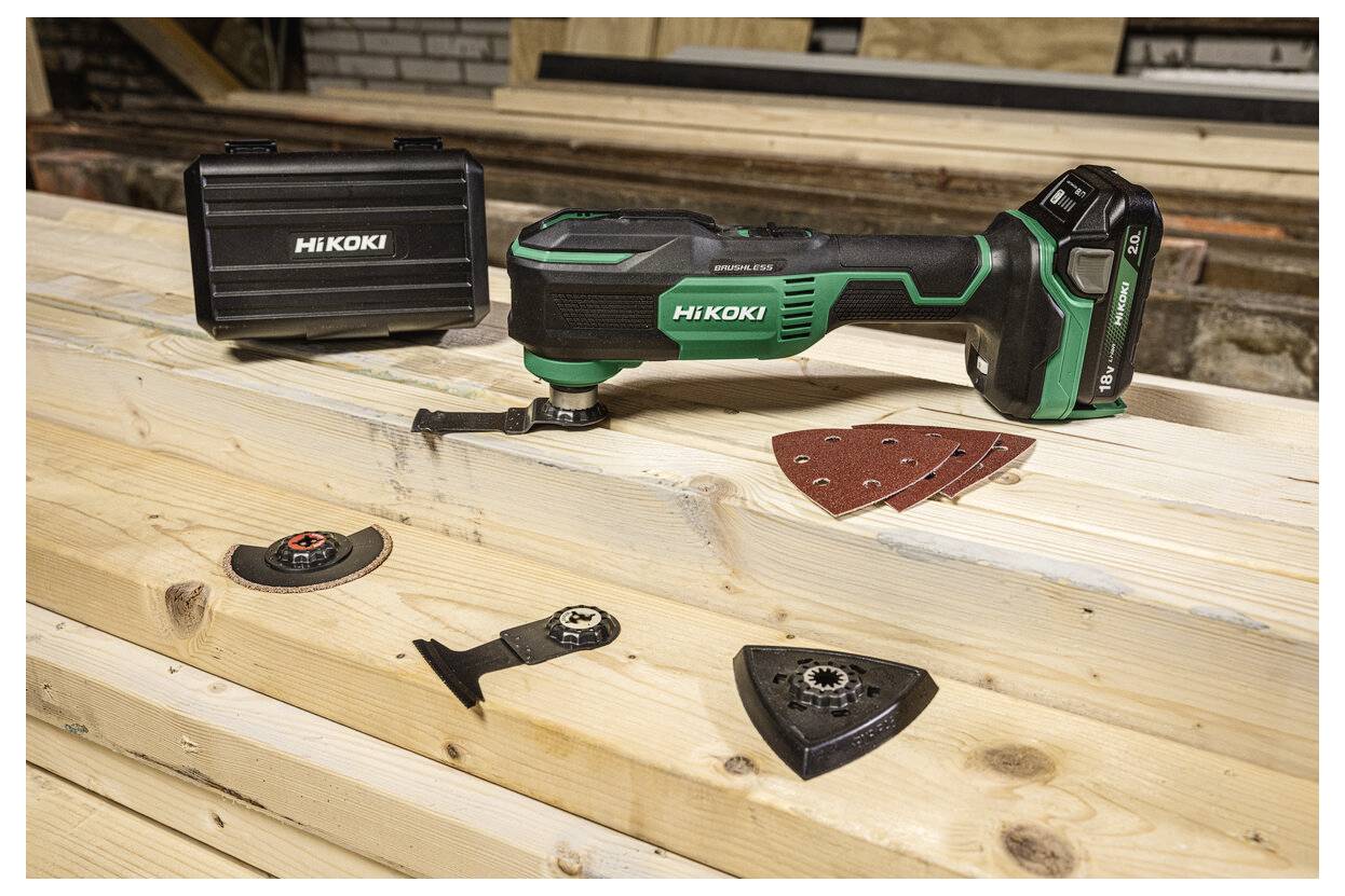 Narzędzie elektryczne na drewnianych deskach z różnymi osprzętami i znajdującą się w pobliżu walizką transportową, odpowiednie do zadań szlifowania i cięcia.