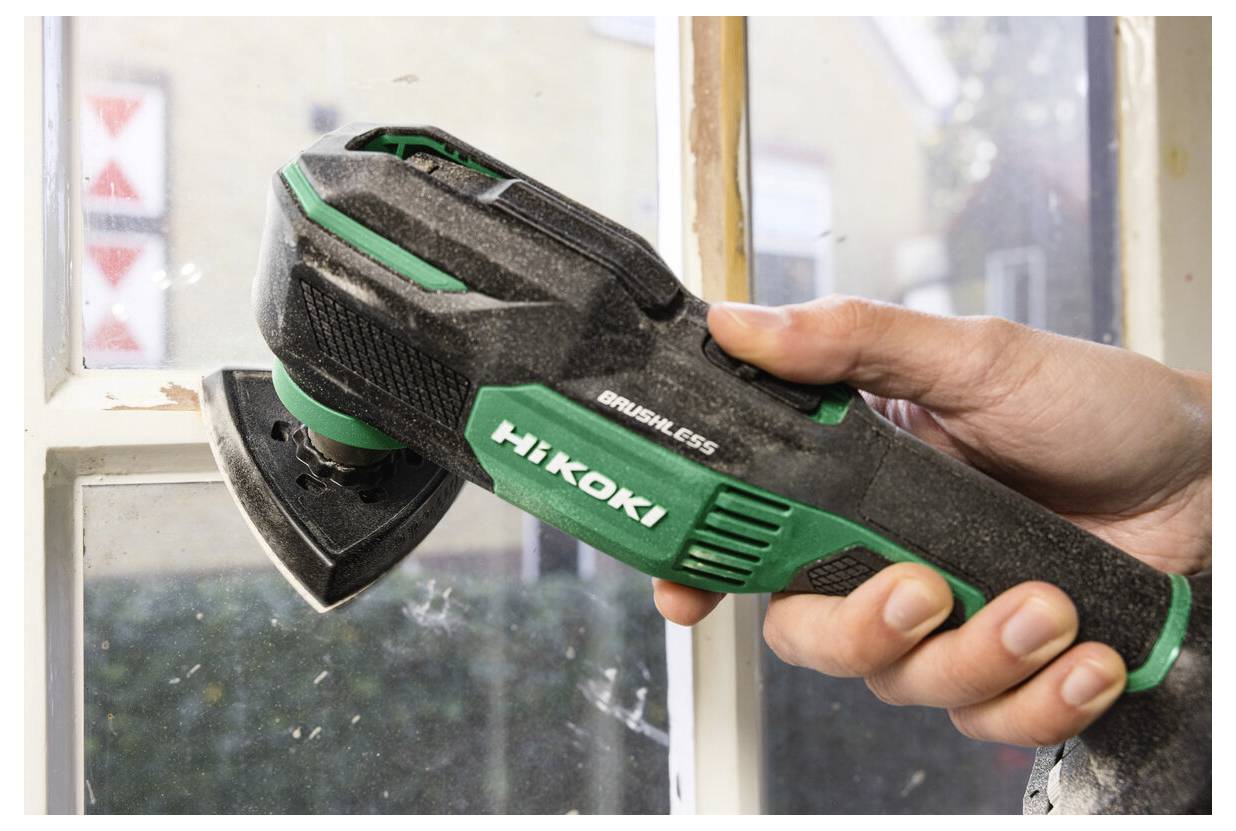 Ręka trzyma elektronarzędzie Hikoki bez szczotek, szlifujące ramę okienną w pomieszczeniu, z Focus na narzędziu i jego działaniu na drewnianej powierzchni.