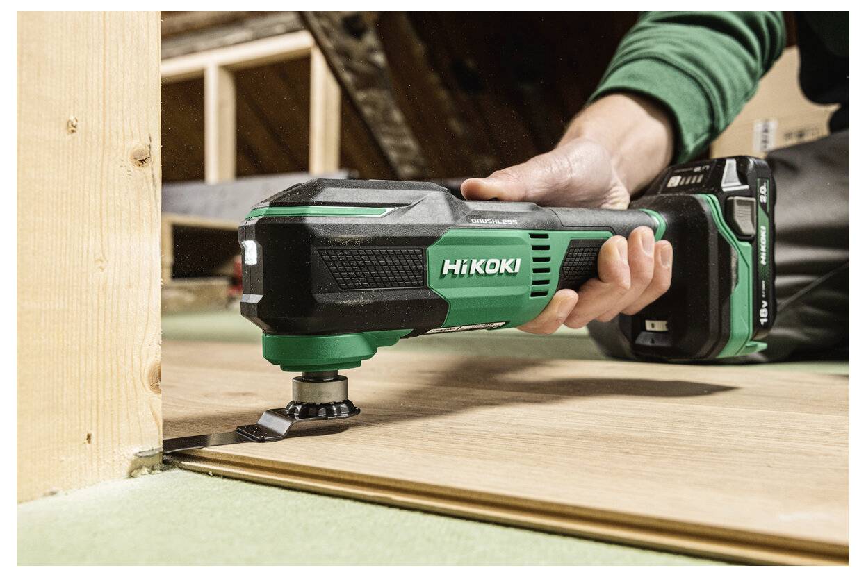 Osoba używa zielonego i czarnego narzędzia oscylacyjnego HiKOKI do cięcia drewnianej płyty, prezentując jego precyzję i wydajność w pracach budowlanych.