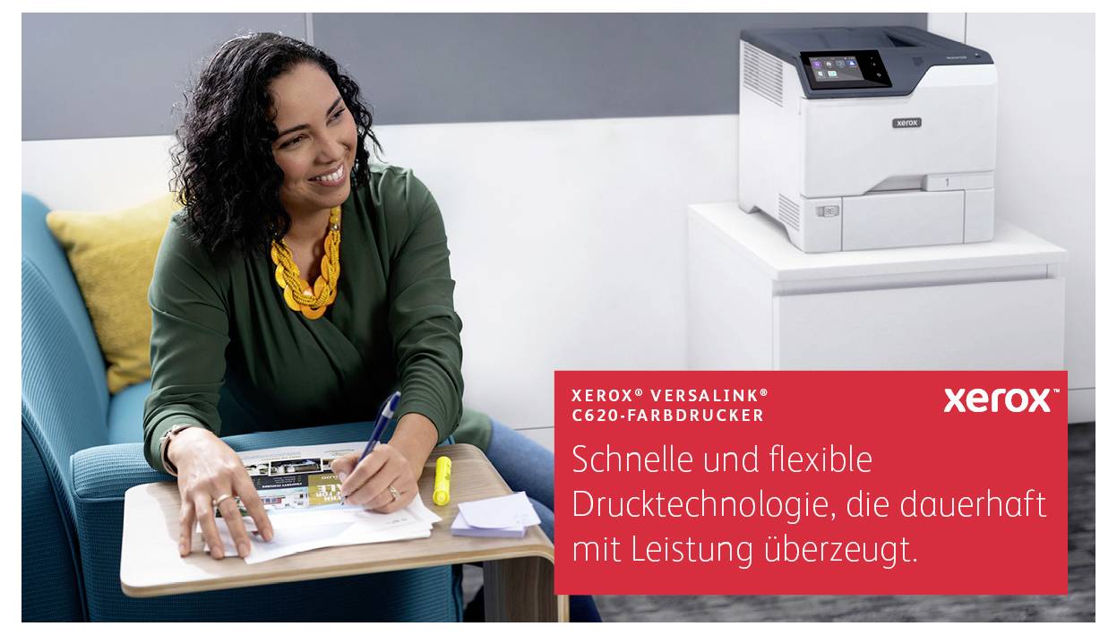 Kobieta siedzi na krześle i uśmiecha się, podczas gdy pisze przy stole. Obok niej znajduje się kolorowa drukarka Xerox.