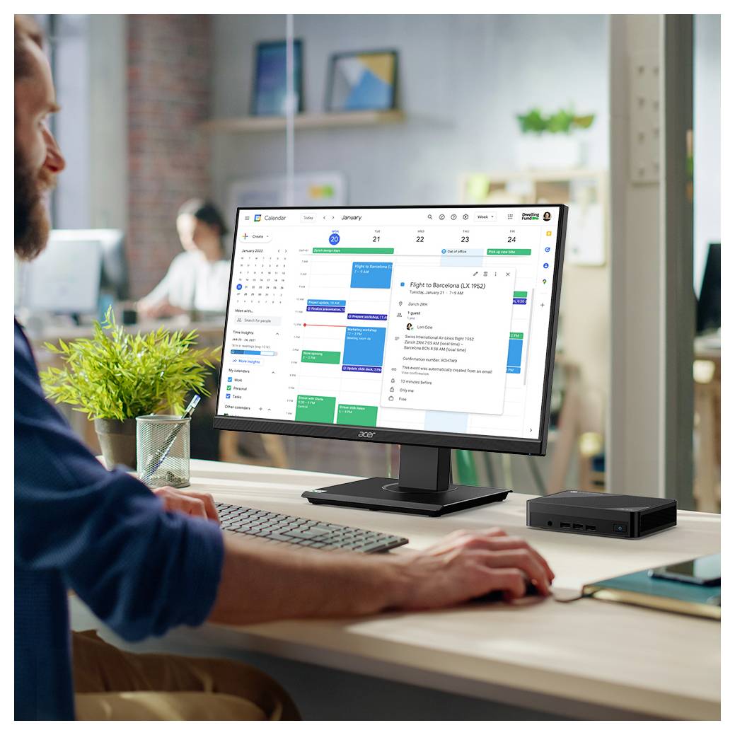 Osoba pracująca przy biurku z monitorem komputera wyświetlającym cyfrowy kalendarz i e-maile, sugerująca skoncentrowane środowisko pracy.