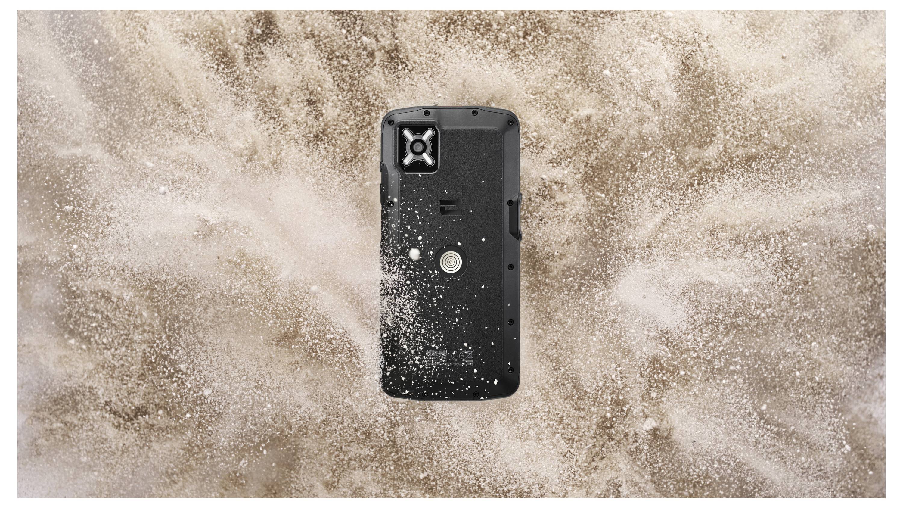 Wytrzymały smartfon otoczony chmurą piasku, prezentujący swoją odporność i wytrzymałość w ekstremalnych warunkach.