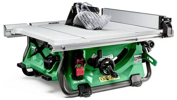 Zielona pilarka stołowa z srebrnym blatem i czarną osłoną bezpieczeństwa, używana do cięcia drewna. Posiada pokrętło regulacyjne i wyłącznik bezpieczeństwa.