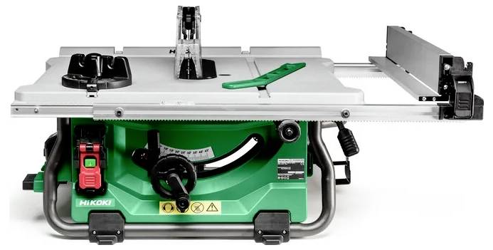 Szara i zielona piła stołowa z czarnym włącznikiem, czerwonym przyciskiem bezpieczeństwa oraz regulowaną prowadnicą do precyzyjnego cięcia drewna.