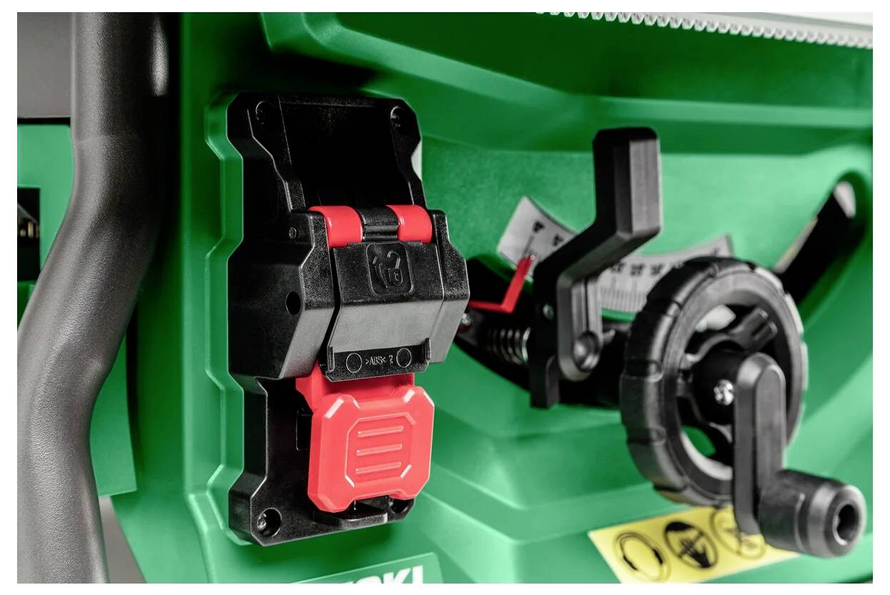 Zbliżony widok zielonej maszyny z czarnymi i czerwonymi przełącznikami i dźwigniami, przedstawiający mechanizmy sterujące do obsługi urządzenia.