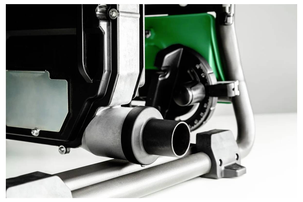 Zbliżenie fragmentu maszyny przemysłowej, przedstawiające czarno-srebrny element na zielonym tle, sugerujące funkcjonalność i wytrzymałość.