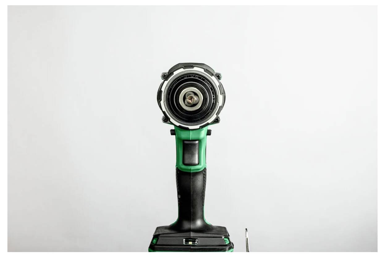 Zielono-czarna akumulatorowa wiertarka udarowa, sfotografowana od przodu, z widocznym uchwytem wiertarskim i spustem, umieszczona na jednolitym białym tle.