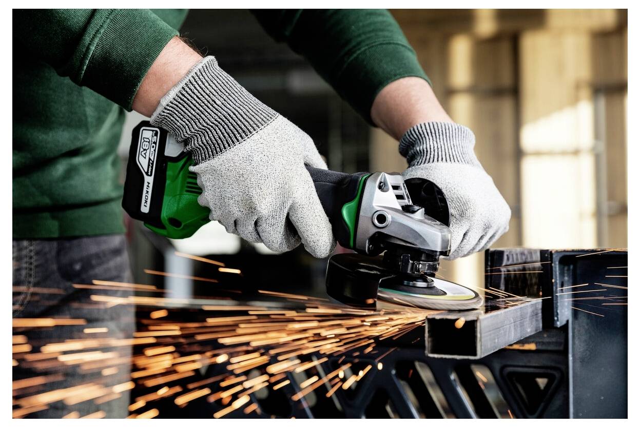 Osoba w rękawicach używa szlifierki kątowej, tworząc jasne iskry podczas cięcia metalowego przedmiotu.