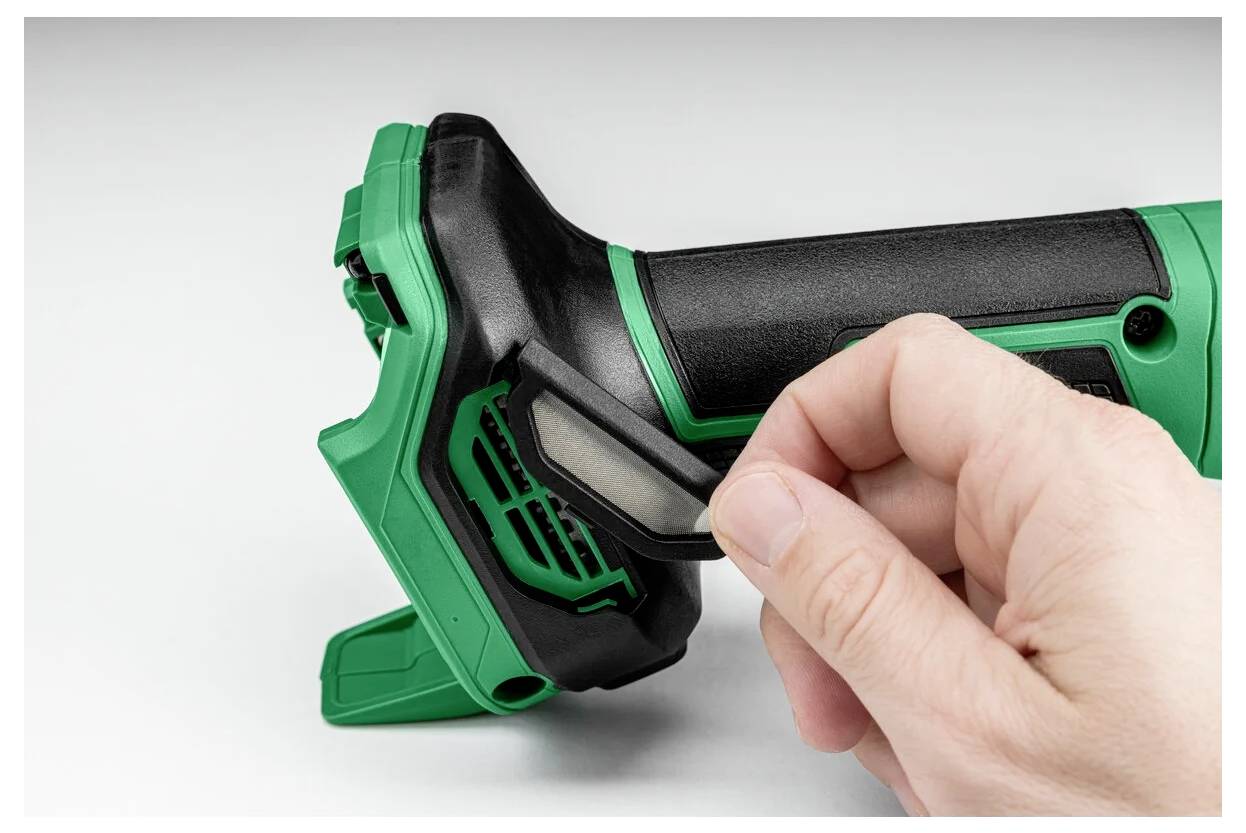 Ręka otwiera komorę baterii przenośnego elektronarzędzia. Narzędzie jest zielono-czarne z teksturowanym uchwytem zapewniającym dobrą przyczepność.