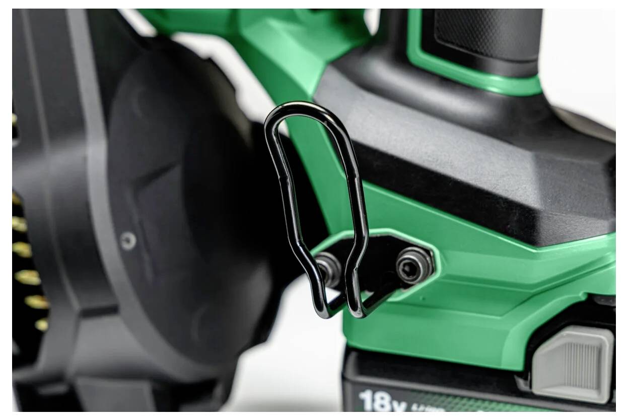 Zbliżenie zielonego i czarnego narzędzia elektrycznego z metalowym haczykiem mocowanym do uchwytu do zawieszania, częściowo widoczny akumulator 18V.