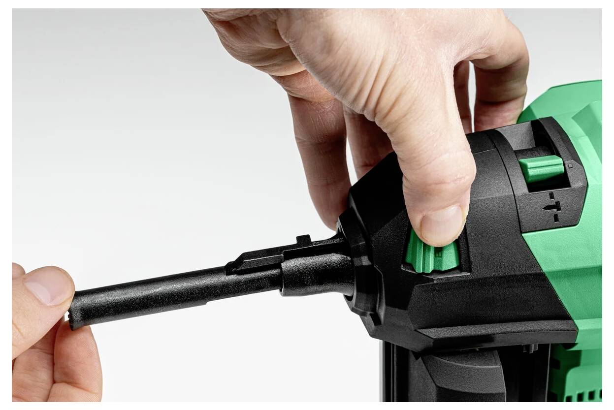 Zbliżenie dłoni wkładającej wiertło do zielonej i czarnej wiertarki, prezentujące montaż narzędzia.