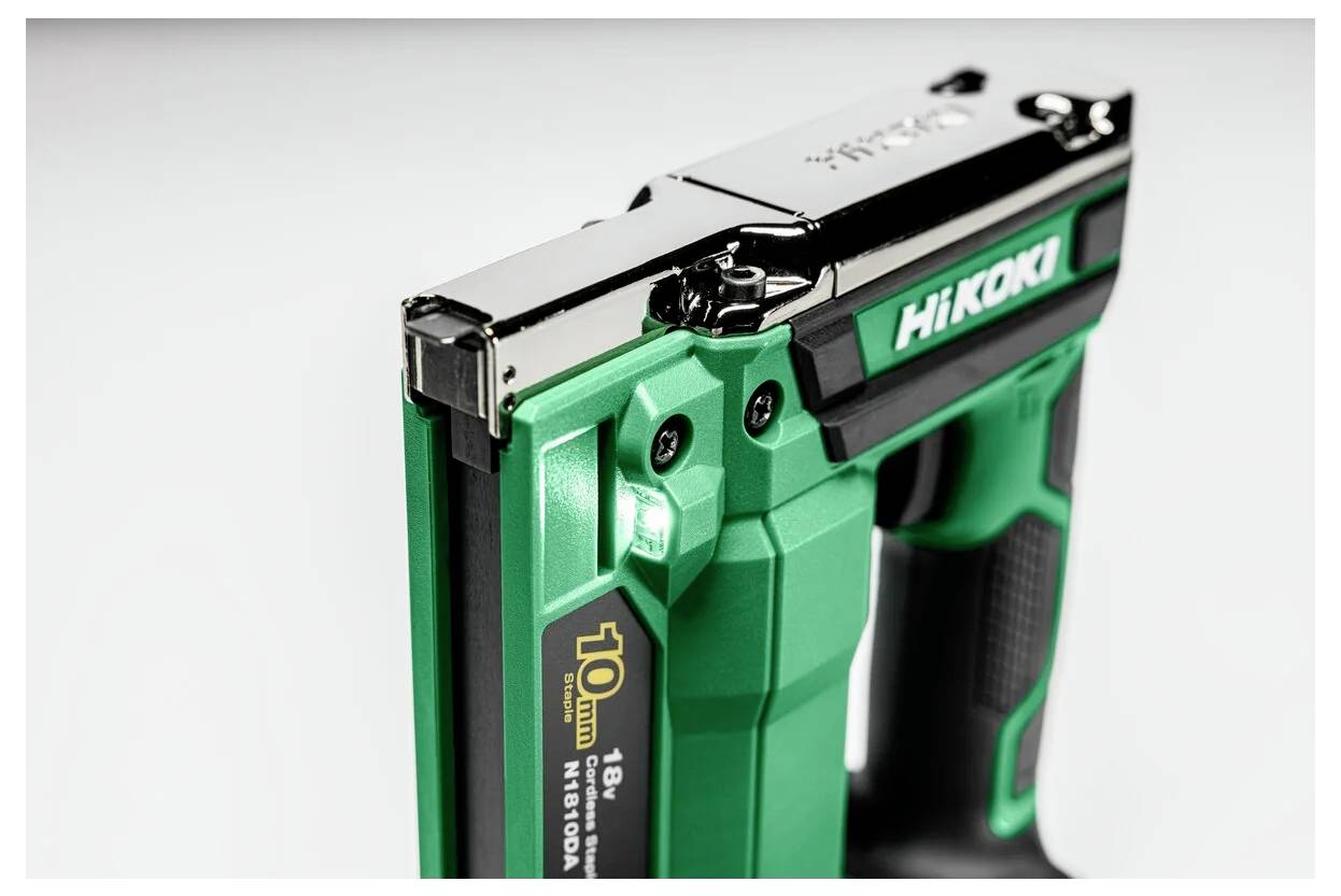 Zielona i czarna zszywarka elektryczna z chromowanymi akcentami, oznaczona etykietą 'HiKOKI'. Widoczna specyfikacja zszywek 10mm, zbliżenie skupione na szczegółach narzędzia.