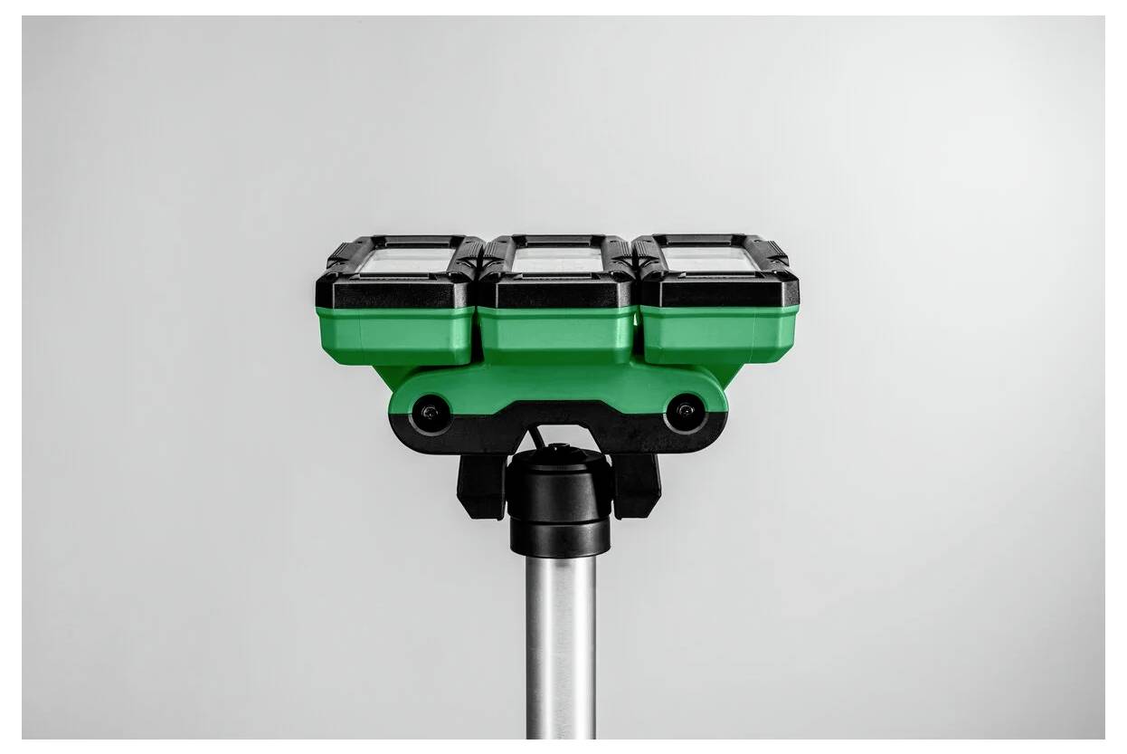 Zielono-czarne urządzenie laserowe do poziomowania zamontowane na statywie na jednolitym tle.
