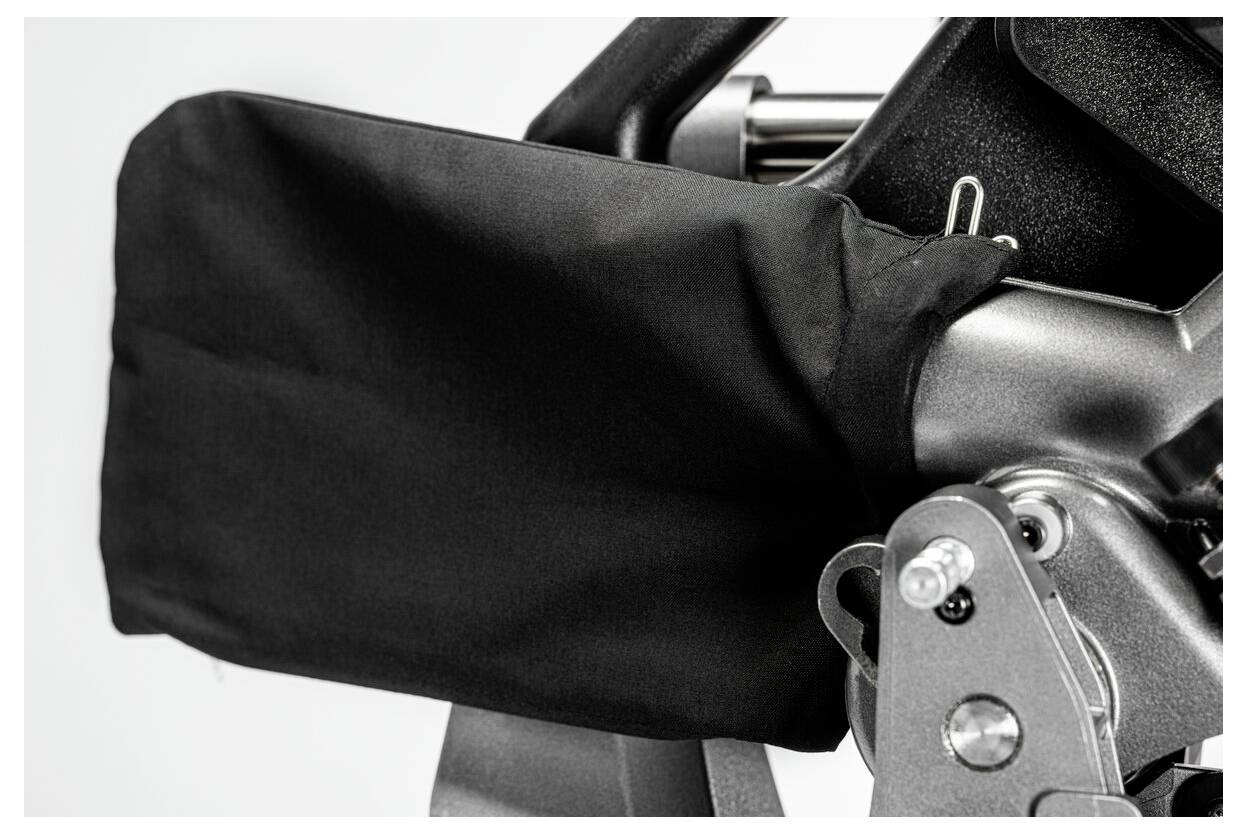 Zbliżenie fragmentu zakrytej części maszyny, z czarnym płóciennym pokrowcem osłaniającym metalowe komponenty, sugerujące ochronę lub ekranowanie.