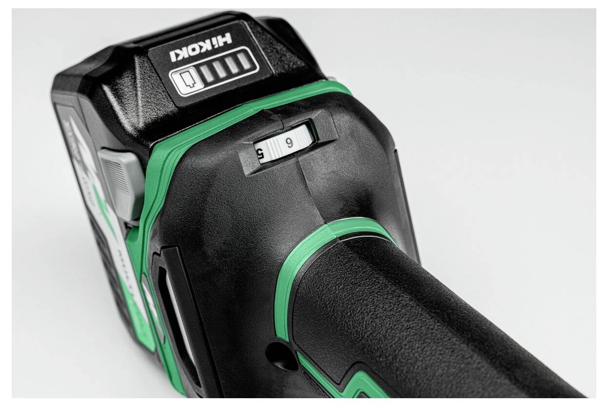 Zbliżenie czarno-zielonej baterii do elektronarzędzia z przełącznikiem suwakowym wskazującym tryby 'S' i 'H' oraz wskaźnikiem poziomu naładowania baterii na górnej powierzchni.