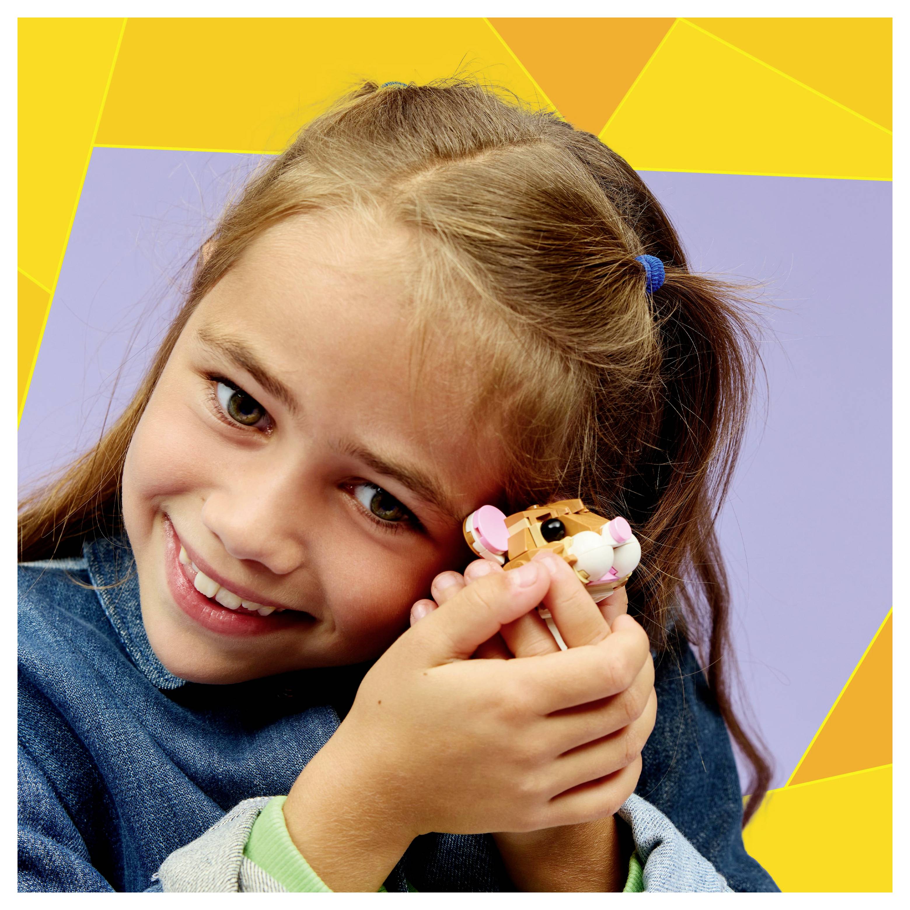 Dziecko uśmiechające się i trzymające małego pluszowego chomika na tle kolorowych geometrycznych kształtów.