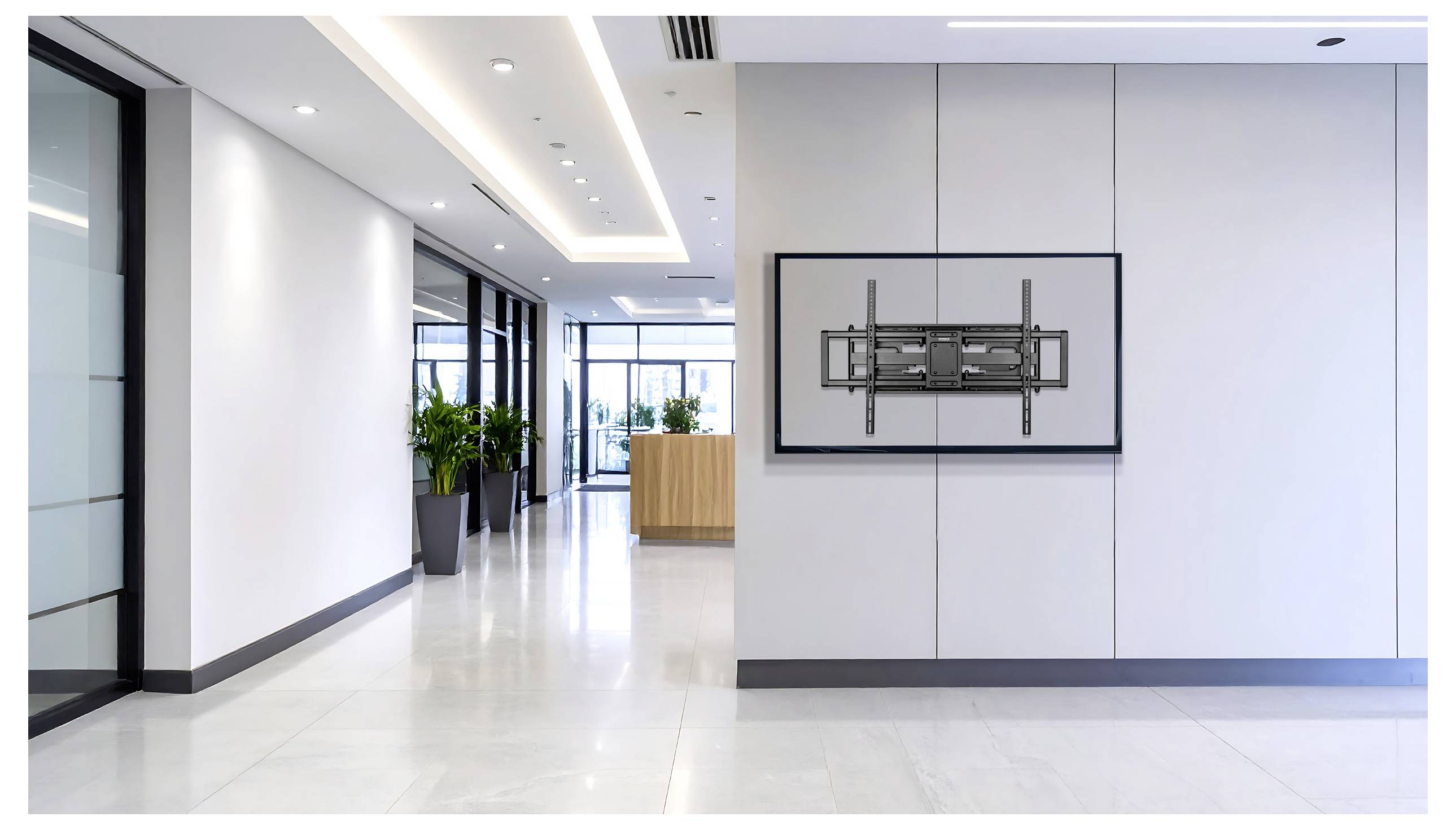 Nowoczesny, jasny korytarz biurowy z dużymi oknami, biurem recepcji w tle i ściennym uchwytem do telewizora bez ekranu.