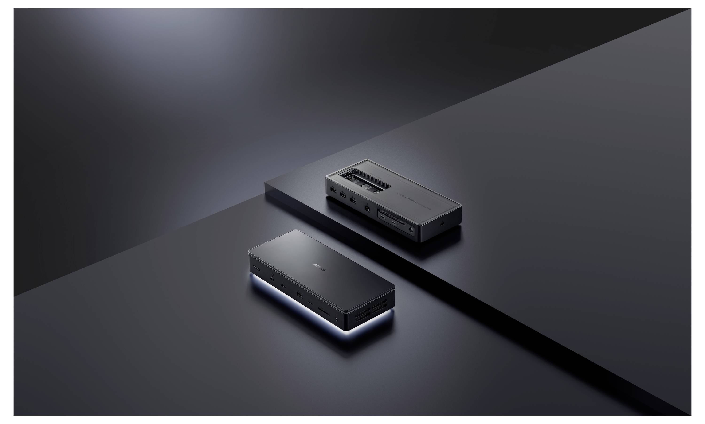 Dwa smukłe czarne urządzenia elektroniczne na ciemnej powierzchni, z jednym urządzeniem nieznacznie podniesionym, emitujące miękkie światło z krawędzi.