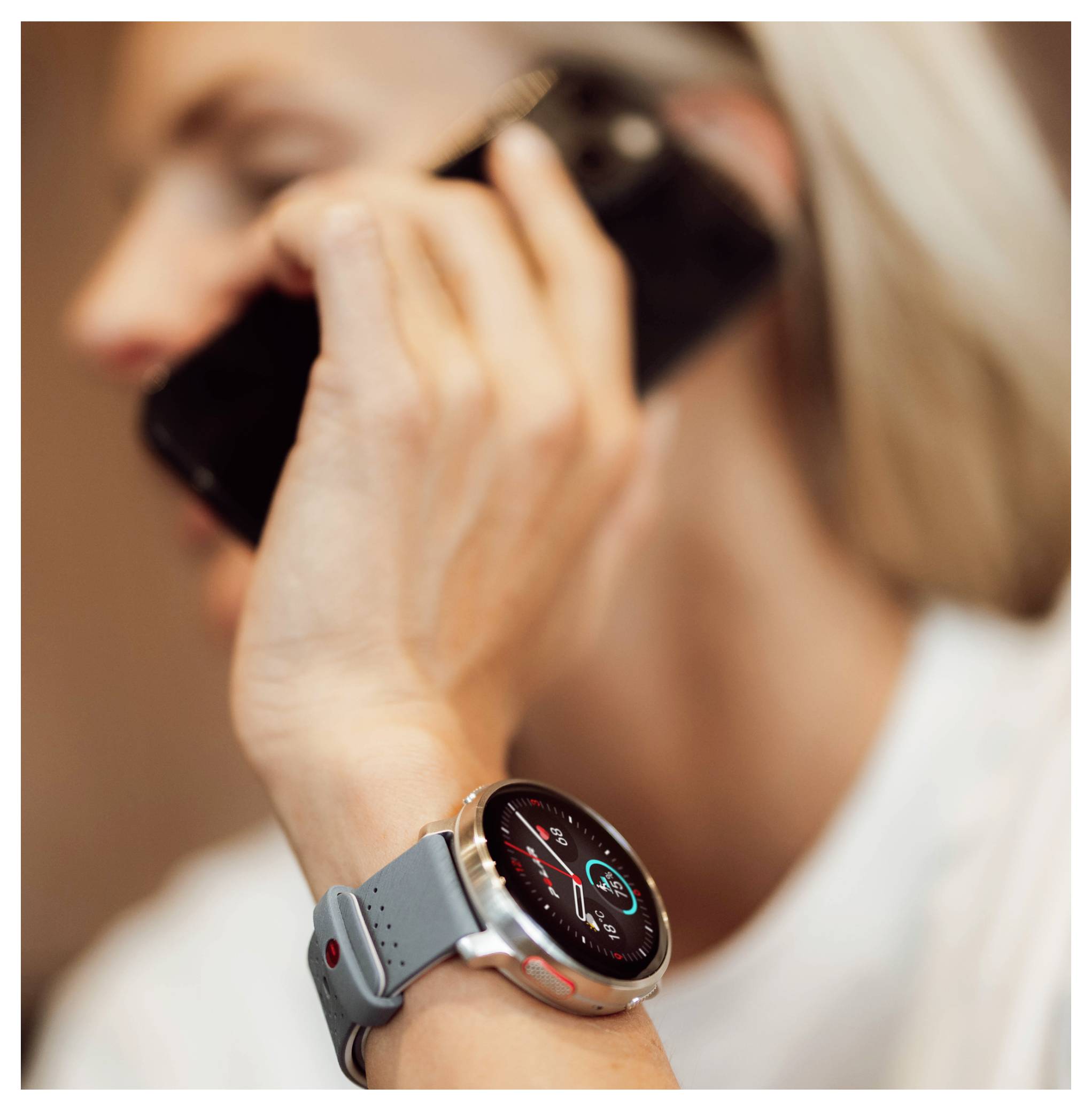 Osoba rozmawiająca przez telefon, nosząca smartwatch wyświetlający dane zdrowotne, takie jak liczba kroków i tętno.