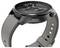 Czarny, nowoczesny smartwatch o eleganckiej sylwetce, wyświetlający analogową tarczę zegarka z trzema subdyslami i okienkiem daty, zamocowany na szarym pasku.