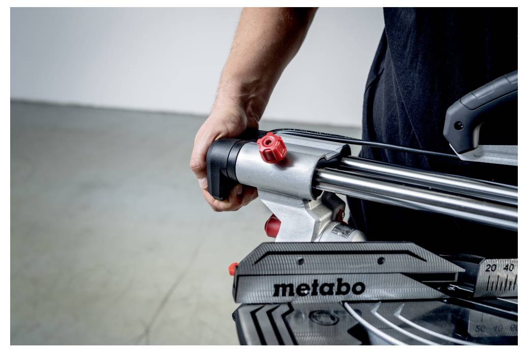 „Osoba obsługuje piłę Metabo, mocno trzymając uchwyt, co wskazuje na bezpieczne i precyzyjne posługiwanie się narzędziem w warsztacie."