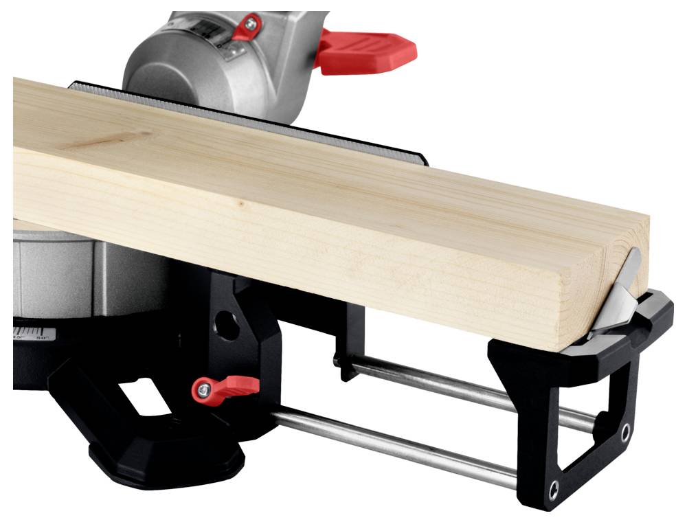 Beżowa drewniana deska jest zaciśnięta w metalowym regulowanym imadle, z czerwonymi i czarnymi uchwytami, co wskazuje na proces obróbki drewna.