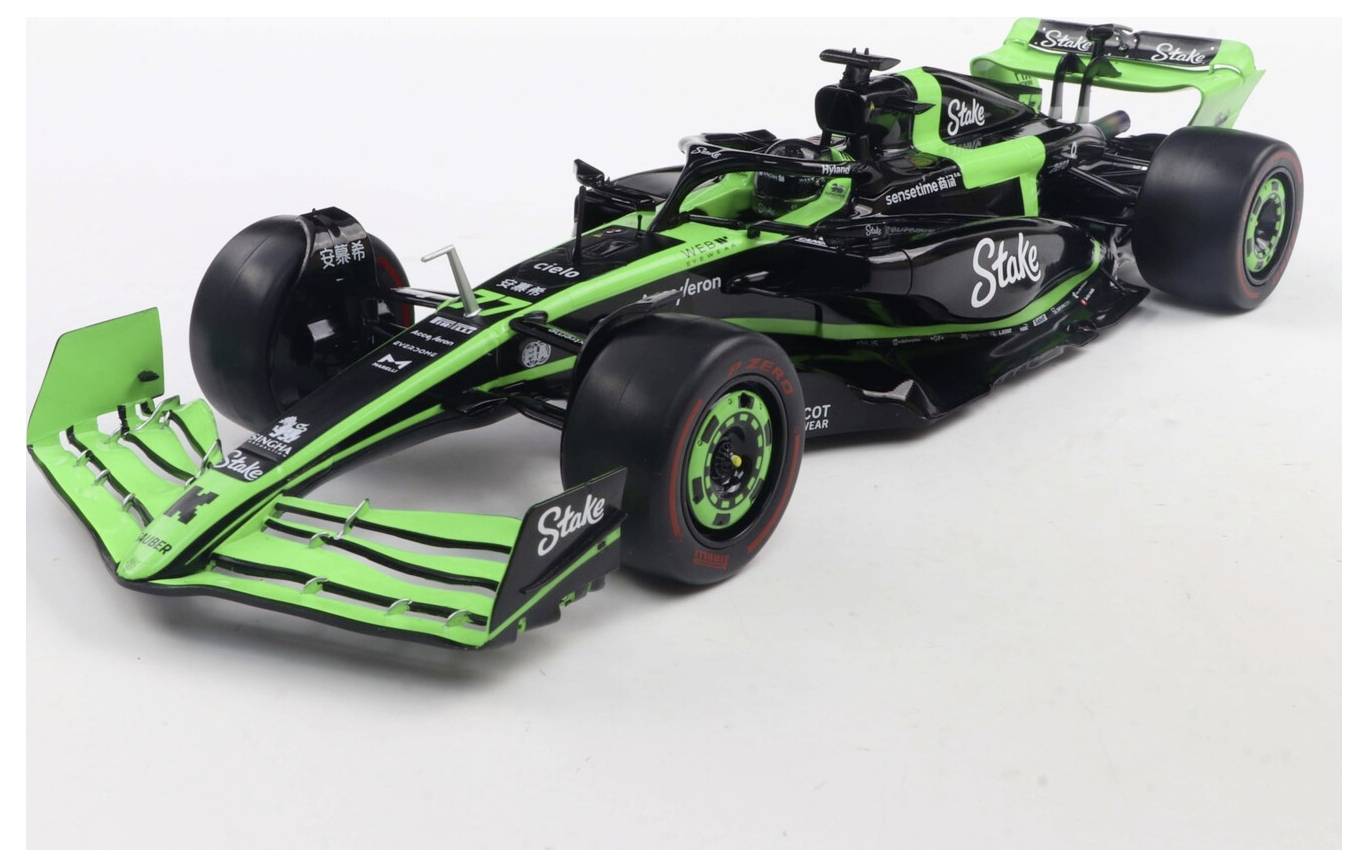 Samochód wyścigowy z malowaniem w kolorach zielonym i czarnym, z napisem 'Stake' na bokach, sfotografowany z przodu pod lewym kątem na białym tle.