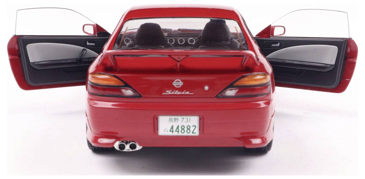 'Widok z tyłu czerwonego Nissana Silvii z otwartymi drzwiami, ukazujący wnętrze i szczegóły deski rozdzielczej.'