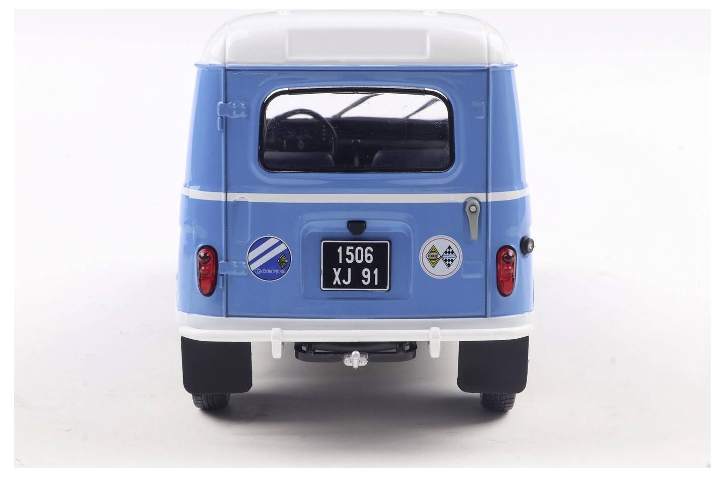 Niebieski zabytkowy van widziany od tyłu, z dwoma okrągłymi naklejkami i czarną tablicą rejestracyjną z białymi numerami '1506 XJ 91'.