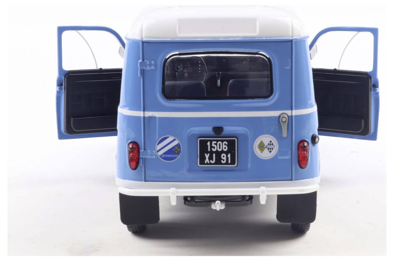 Niebieski zabytkowy model van z otwartymi tylnymi drzwiami posiada tablicę rejestracyjną '1506 XJ 91' oraz okrągłe naklejki. Wnętrze pojazdu jest widoczne.