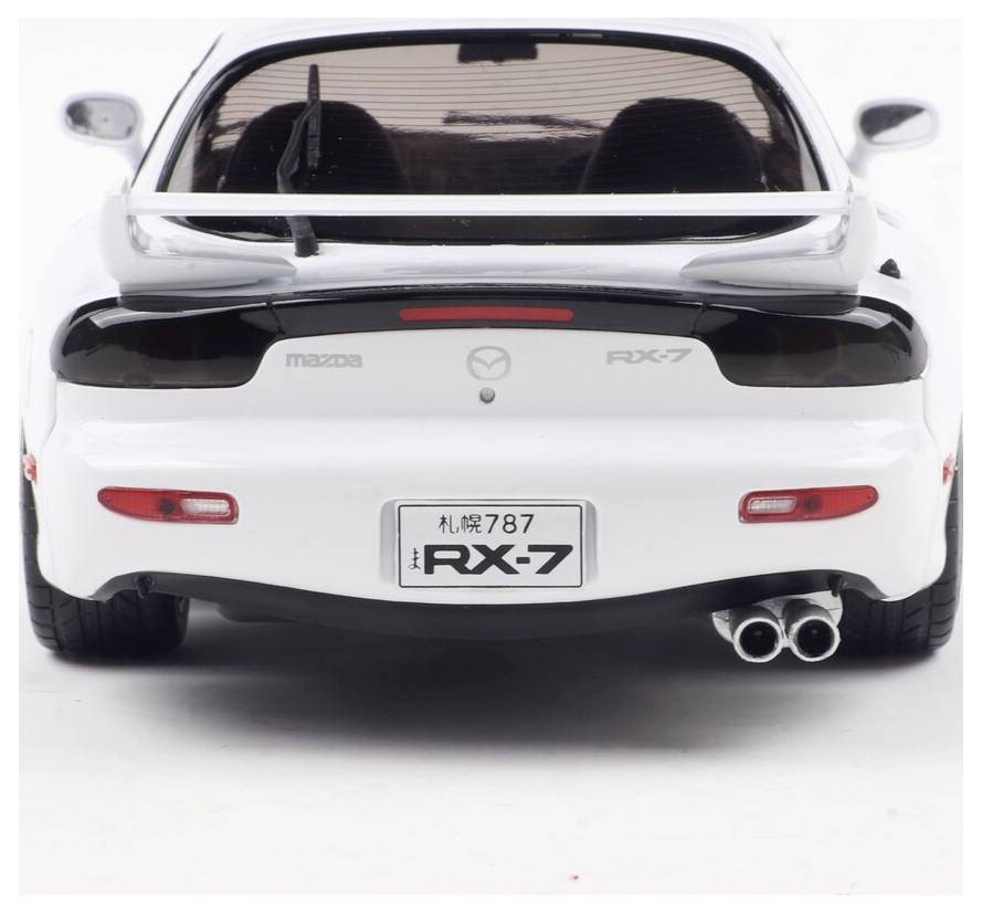 Biały samochód sportowy widziany od tyłu, prezentujący spojler, podwójny układ wydechowy oraz znaczek 'RX-7'. Tablica rejestracyjna wskazuje '787'.