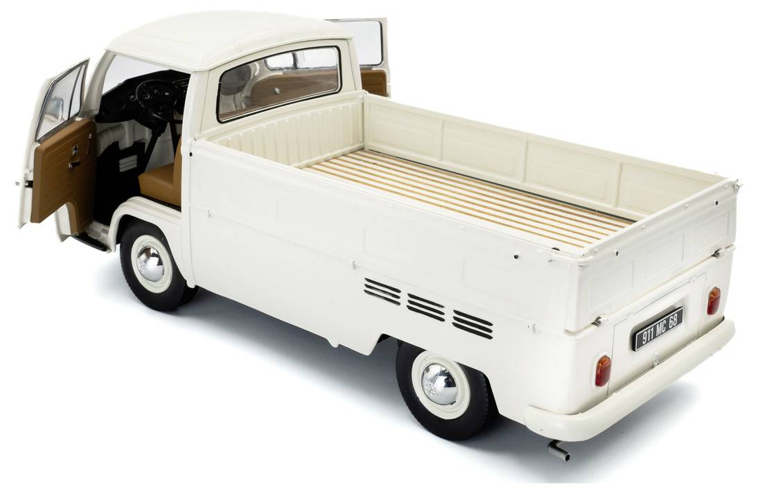 Zabytkowy biały samochód pickup z otwartymi drzwiami po stronie kierowcy, prezentujący przestronną skrzynię ładunkową wyłożoną pasiastym materiałem.