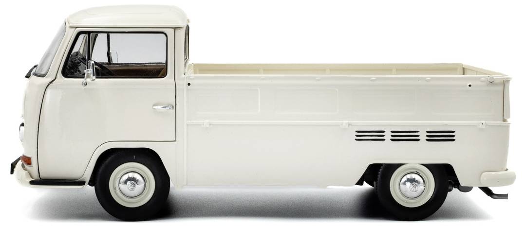 Klasyczny, biały zabytkowy pickup oglądany z boku, prezentujący swoją opływową sylwetkę i retro elementy.