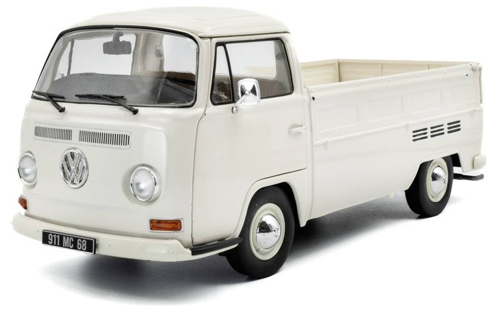 Zabytkowa biała furgonetka Volkswagena w stylu retro, z klasycznym logo VW z przodu i platformą ładunkową z tyłu.