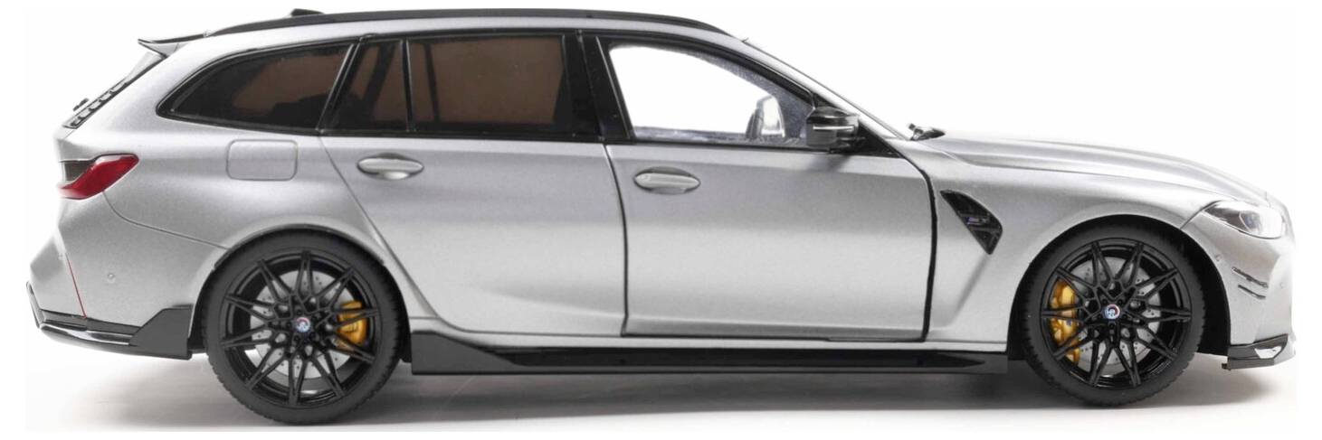 Srebrny luksusowy samochód kombi z czarnymi felgami i pomarańczowymi zaciskami hamulcowymi, widziany z boku na białym tle.