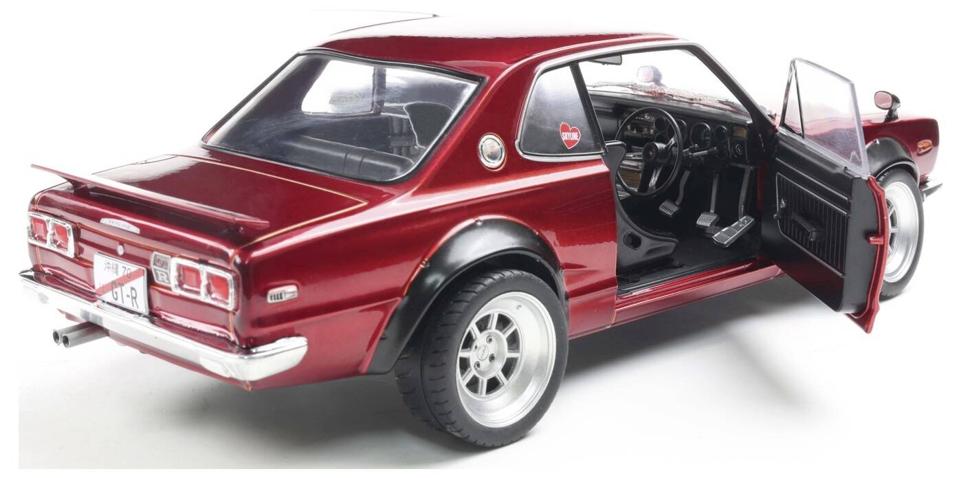 Zabytkowy czerwony samochód z otwartymi drzwiami, prezentujący czarne wnętrze i błyszczące metalowe akcenty, zaparkowany na białej powierzchni.