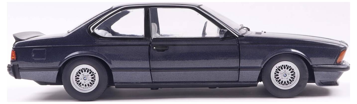 Widok z boku klasycznego, ciemnoniebieskiego dwudrzwiowego coupe z felgami ze stopu metali lekkich, prezentujący jego elegancką sylwetkę na białym, jednolitym tle.