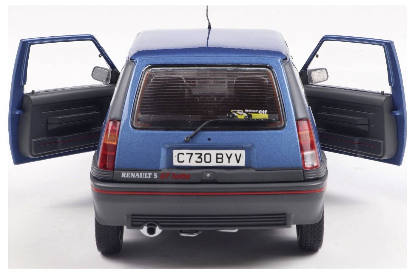 Niebieski Renault 5 GT Turbo jest pokazany od tyłu z otwartą klapą bagażnika i bocznymi drzwiami, ukazując szczegółowe wnętrze samochodu.