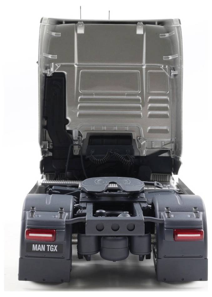 Ciemny samochód ciężarowy z otwartą maską, widziany od tyłu, z widoczną komorą silnika. Na pojeździe widoczny jest model 'MAN TGX'.