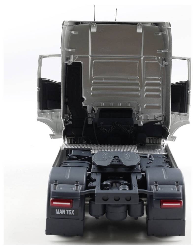 Model ciężarówki z widocznymi częściami silnika. Drzwi kabiny są otwarte, ukazując wnętrze. Na tylnej części widoczna jest marka 'MAN TGX'.