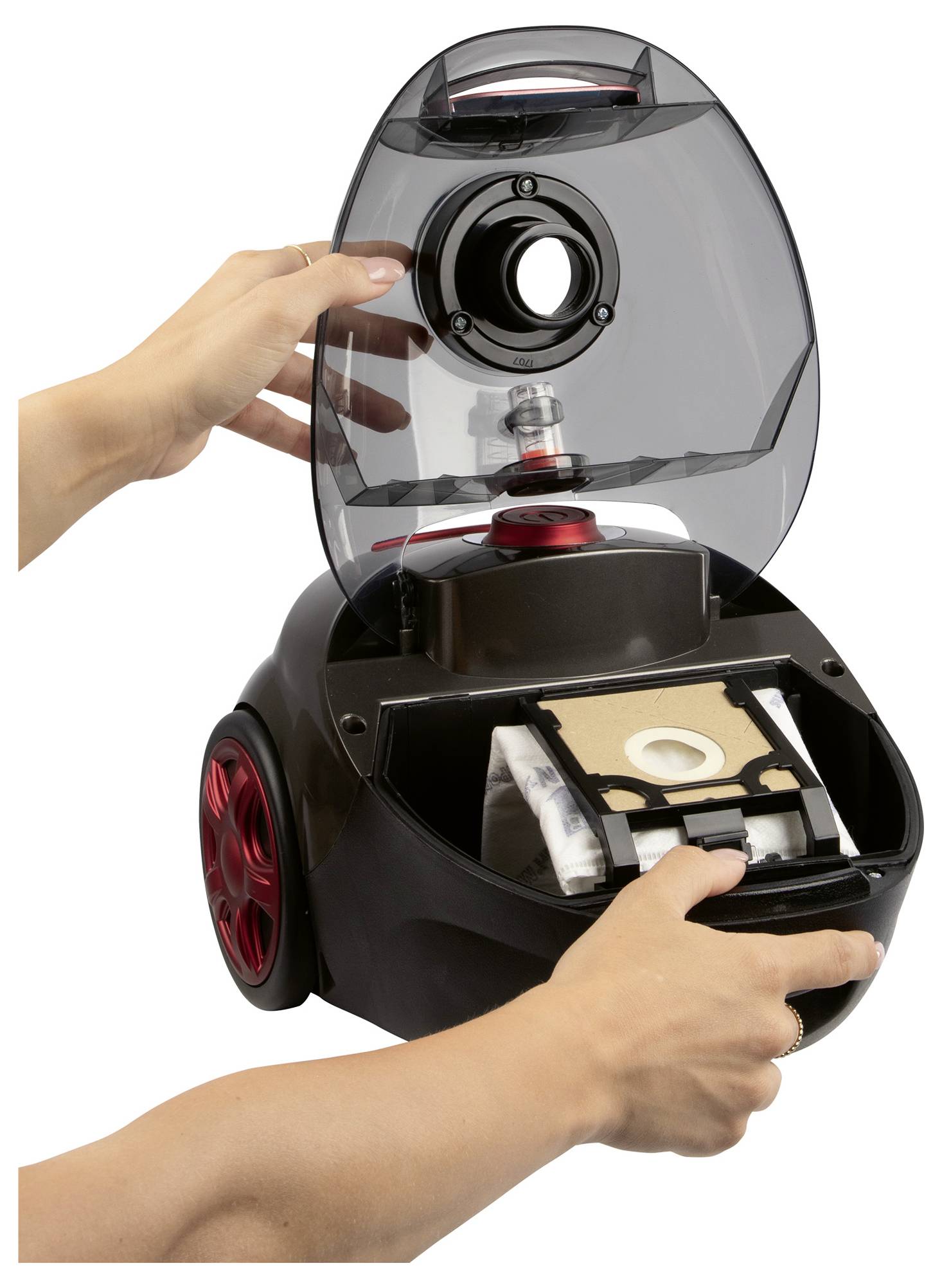 Osoba demonstrująca, jak wymienić worek w odkurzaczu, poprzez otwarcie górnej komory i wyjęcie worka z wewnętrznej sekcji.