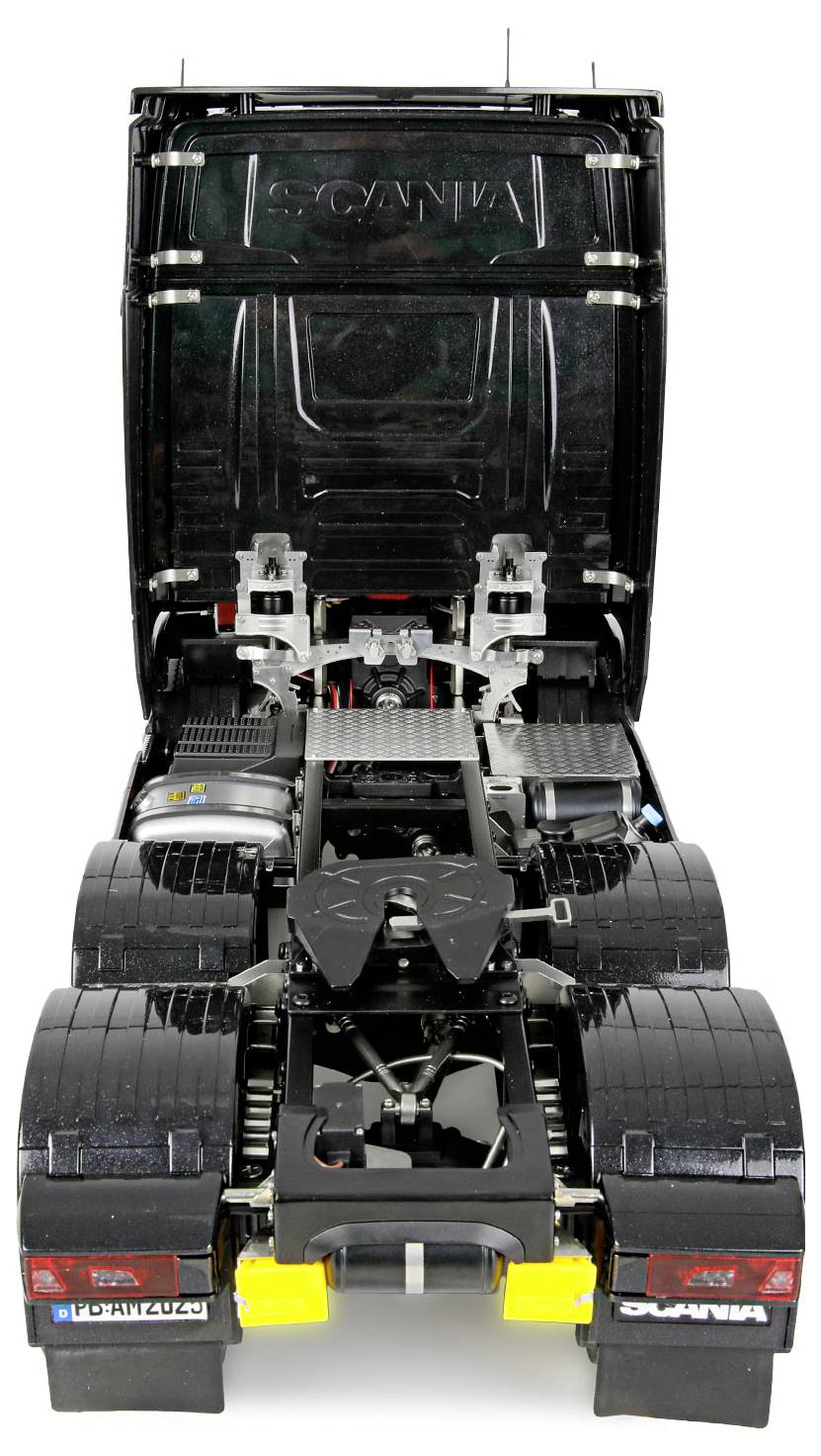Model czarnej ciężarówki z przednią kabiną odchyloną do przodu, ukazujący szczegółowe komponenty silnika i części mechaniczne pod spodem.