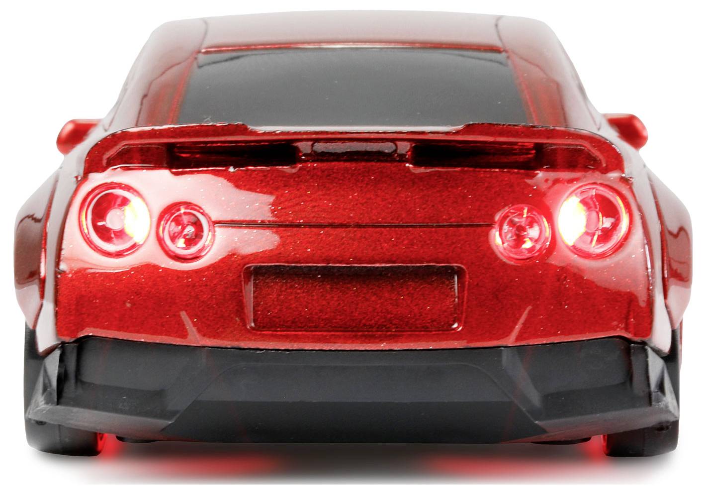 Czerwony samochód sportowy widziany od tyłu z włączonymi światłami tylnymi.