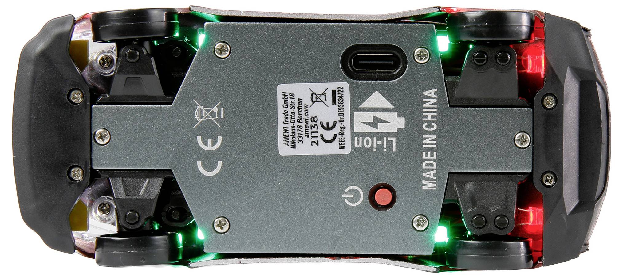 Spodnia strona zabawkowego samochodziku przedstawiająca koła, oznaczenie CE, komorę baterii, przełącznik oraz etykietę "Wyprodukowano w Chinach", wskazujące na pochodzenie i zgodność z normami.