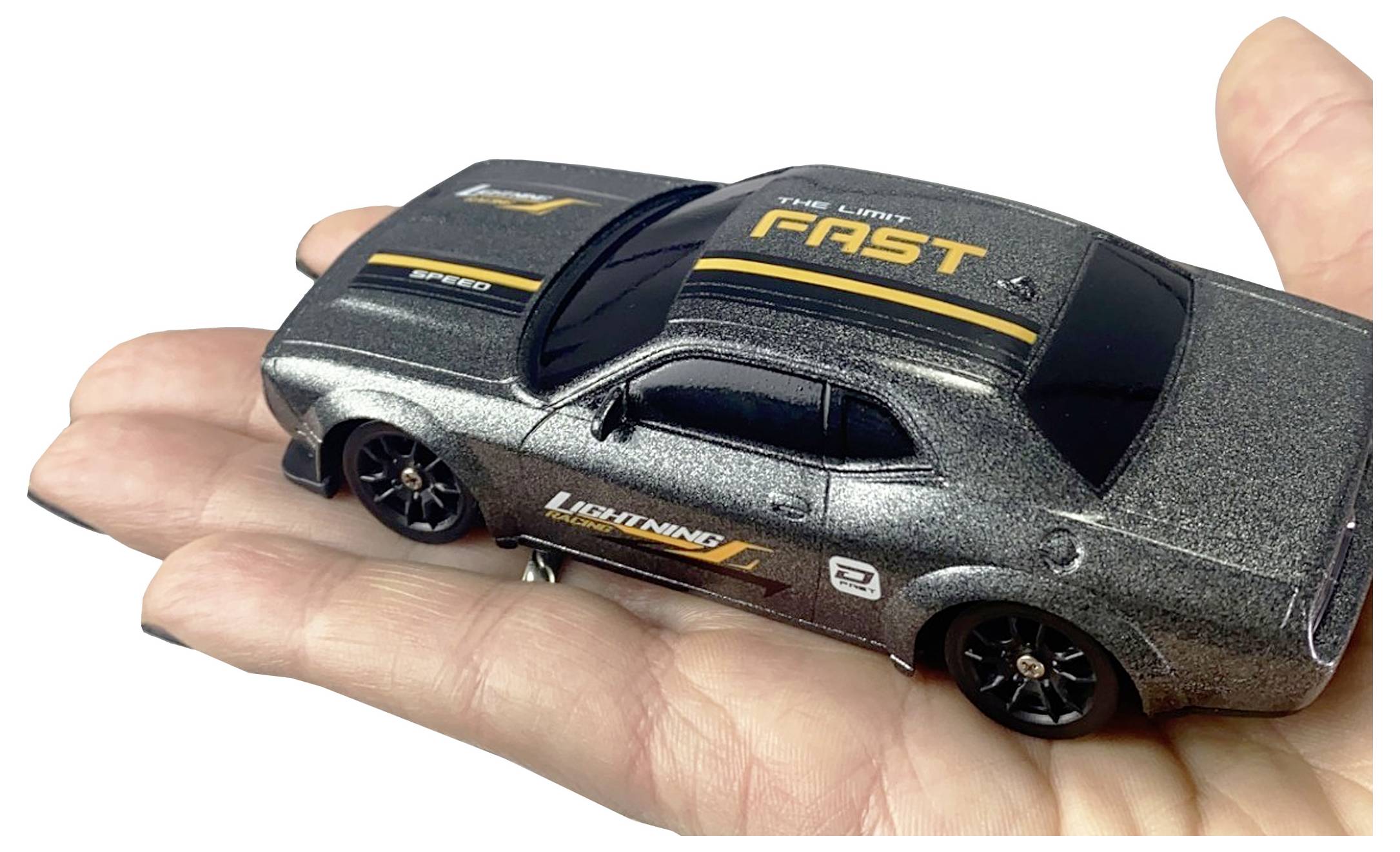 Dłoń trzyma mały metalowy model samochodu z napisem "The Limit is Fast" na dachu oraz "Lightning" z boku, ozdobiony sportowymi naklejkami.
