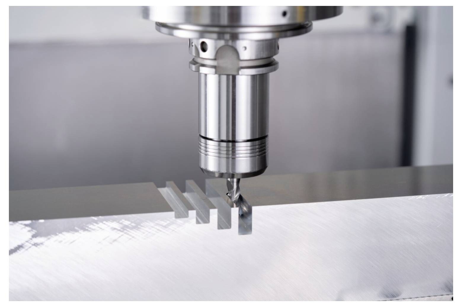 Zbliżenie maszyny CNC precyzyjnie frezującej równoległe rowki na metalowej powierzchni, przedstawiające dokładność obróbki skrawaniem w akcji.