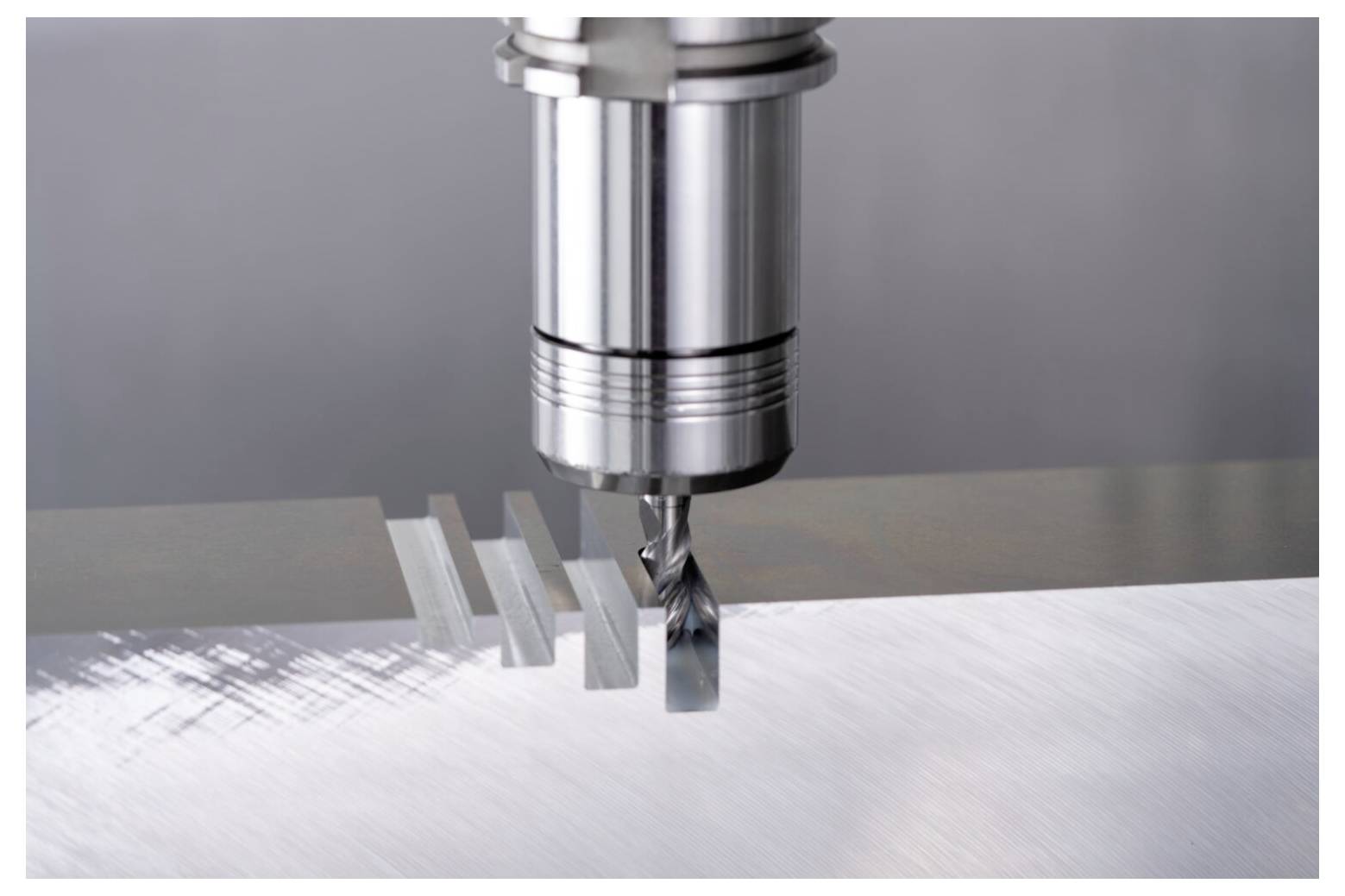 Frezarka wycina rowki w płaskiej powierzchni metalowej, prezentując precyzyjne projektowanie inżynieryjne i technologię obróbki skrawaniem.