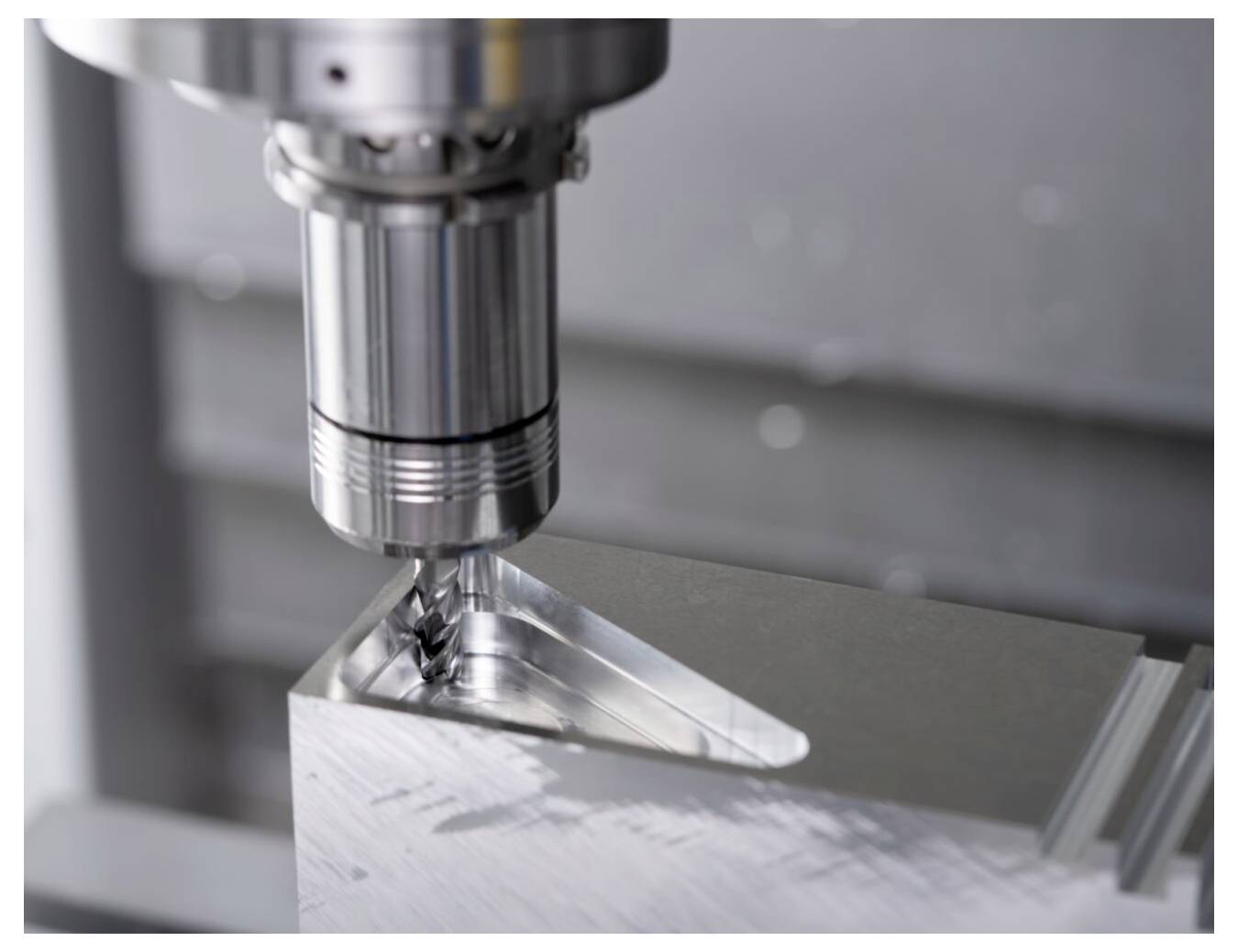 Metalowa maszyna CNC precyzyjnie wiercąca prostokątny blok, ze szczególnym uwzględnieniem styku wiertła z materiałem.