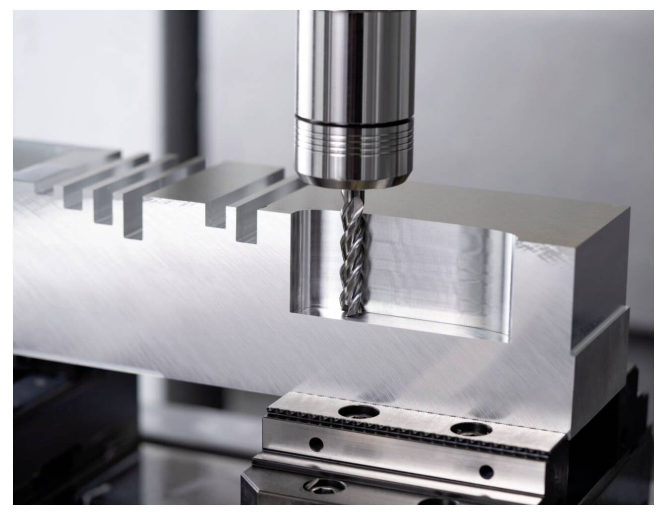 Metalowy blok jest precyzyjnie cięty za pomocą frezarki z obracającym się świdrowym wiertłem, prezentując technologię obróbki przemysłowej.