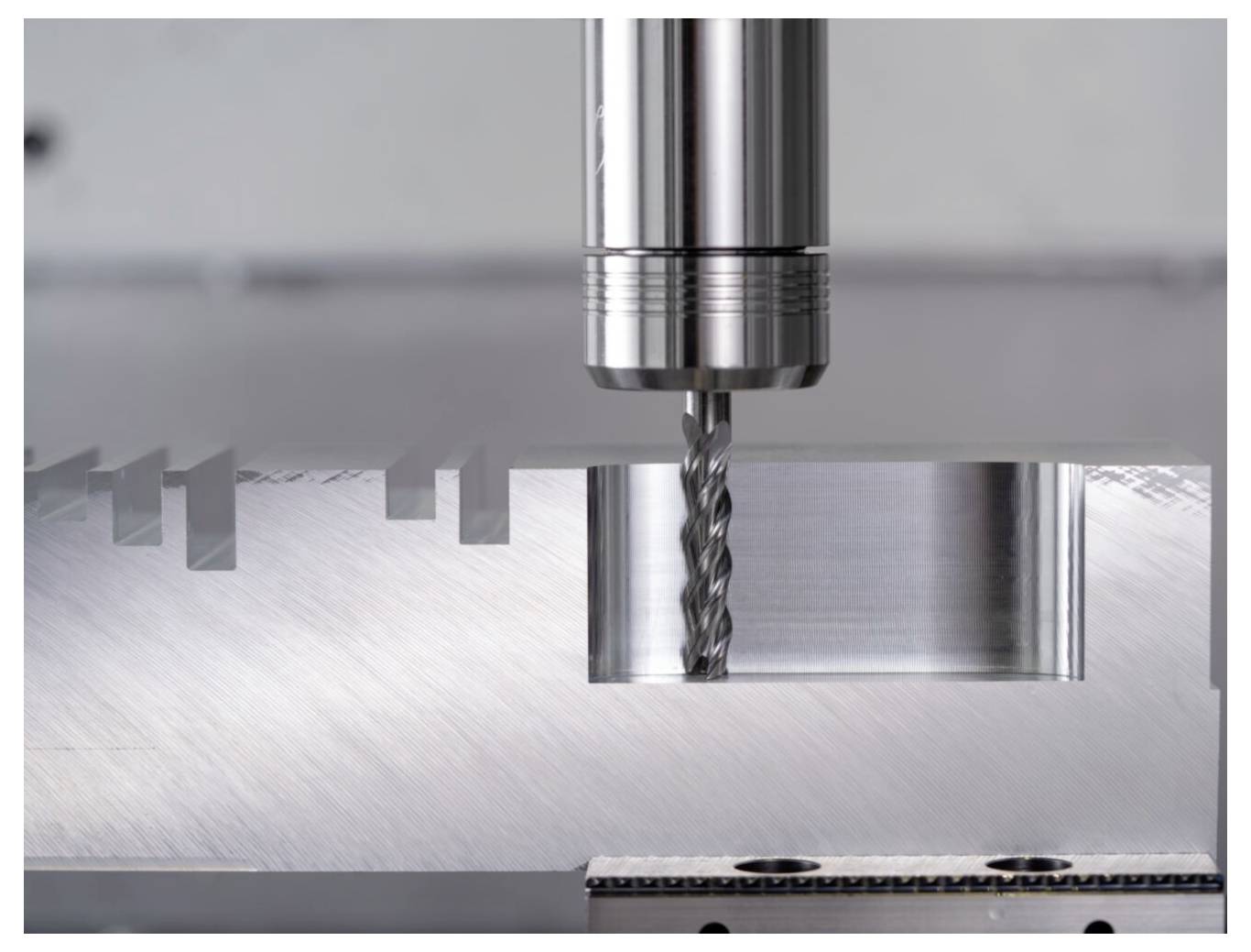 Metalowy wiertnik tworzący precyzyjne rowki na płaskiej metalowej powierzchni, prezentujący postęp obróbki przemysłowej.